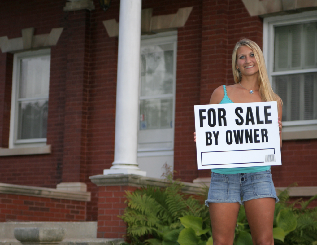 Woman holding a for sale by owner sign